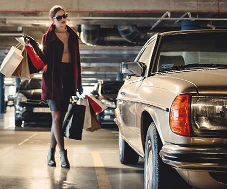woman walking to car with bags of purchased items